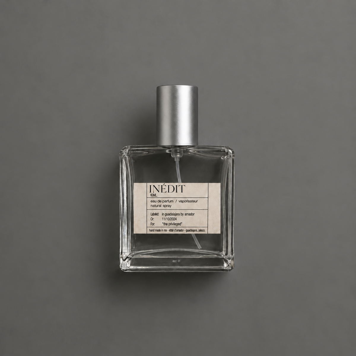 Inédit de Elixir Amador: frasco cuadrado de 60 ml sobre fondo gris.